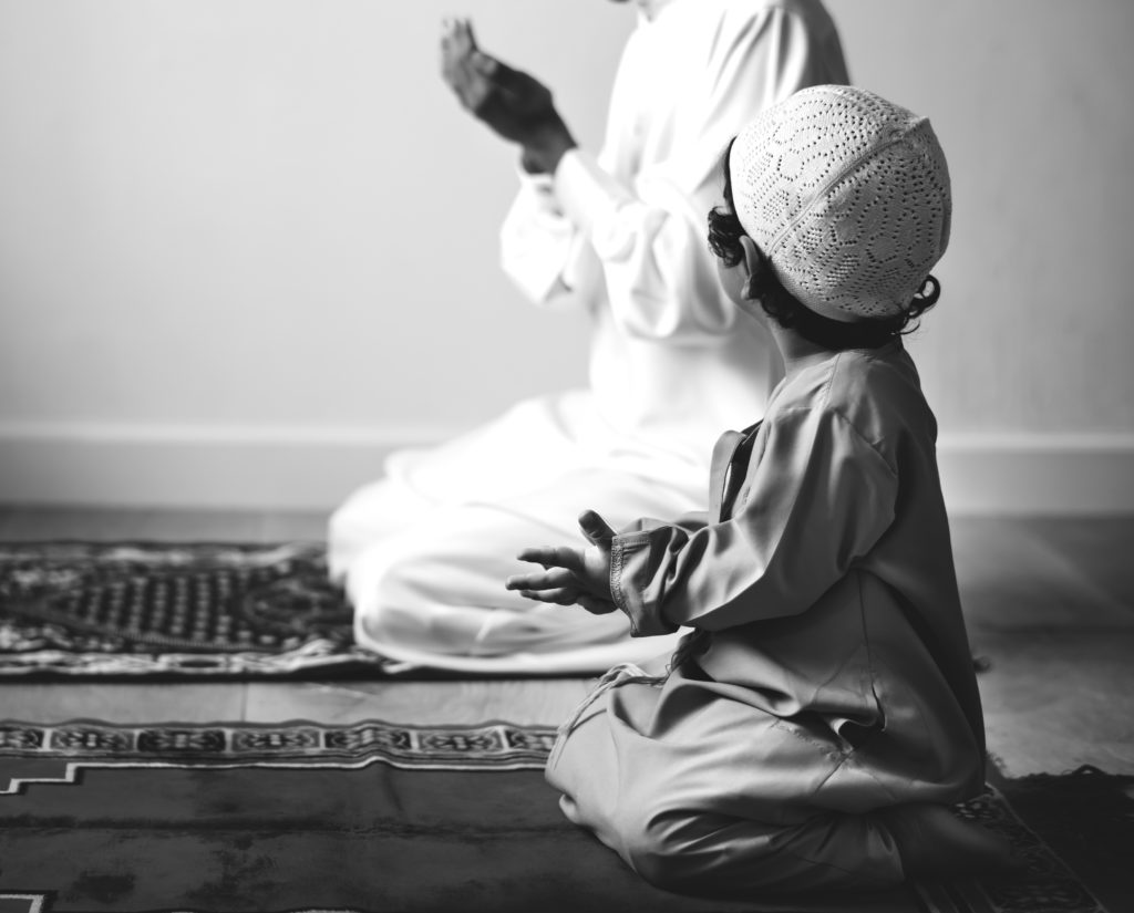 Muslim boy learning how to make Dua to Allah